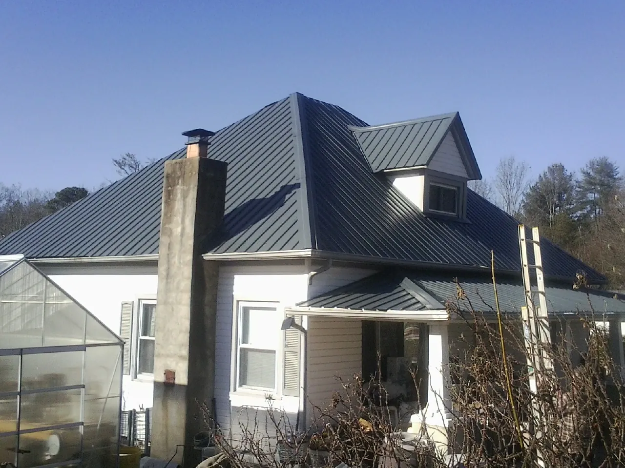 Dark blue standing seam metal roof on a white farmhouse with dormer — Slate & Tile Roof Repair by Roofing Brothers in California