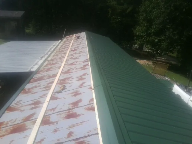Old rusted panels beside newly installed green metal roofing — Wind Damage Roof Repair by Roofing Brothers in California
