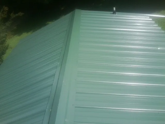 New green metal panels meeting at the ridge of a roof — Flat Roof Repair work by our crew in California