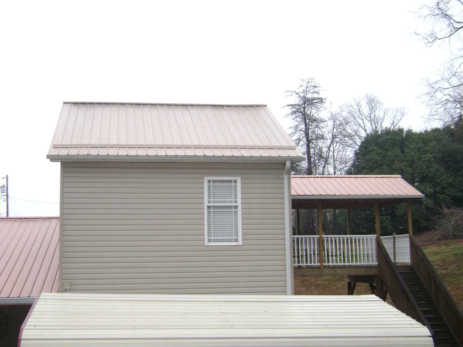 Tan metal roofs on a two story addition and attached porch, from a Roof Replacement job in California